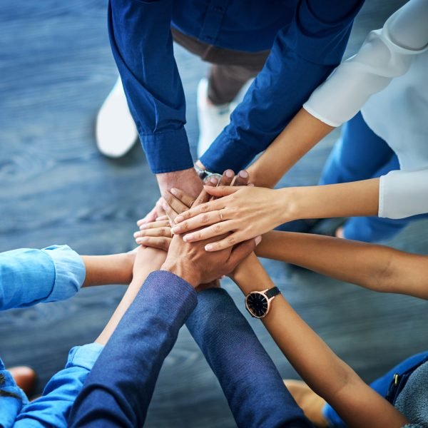 High angle shot of a group unrecognizable businesspeople joining their hands together in unity.